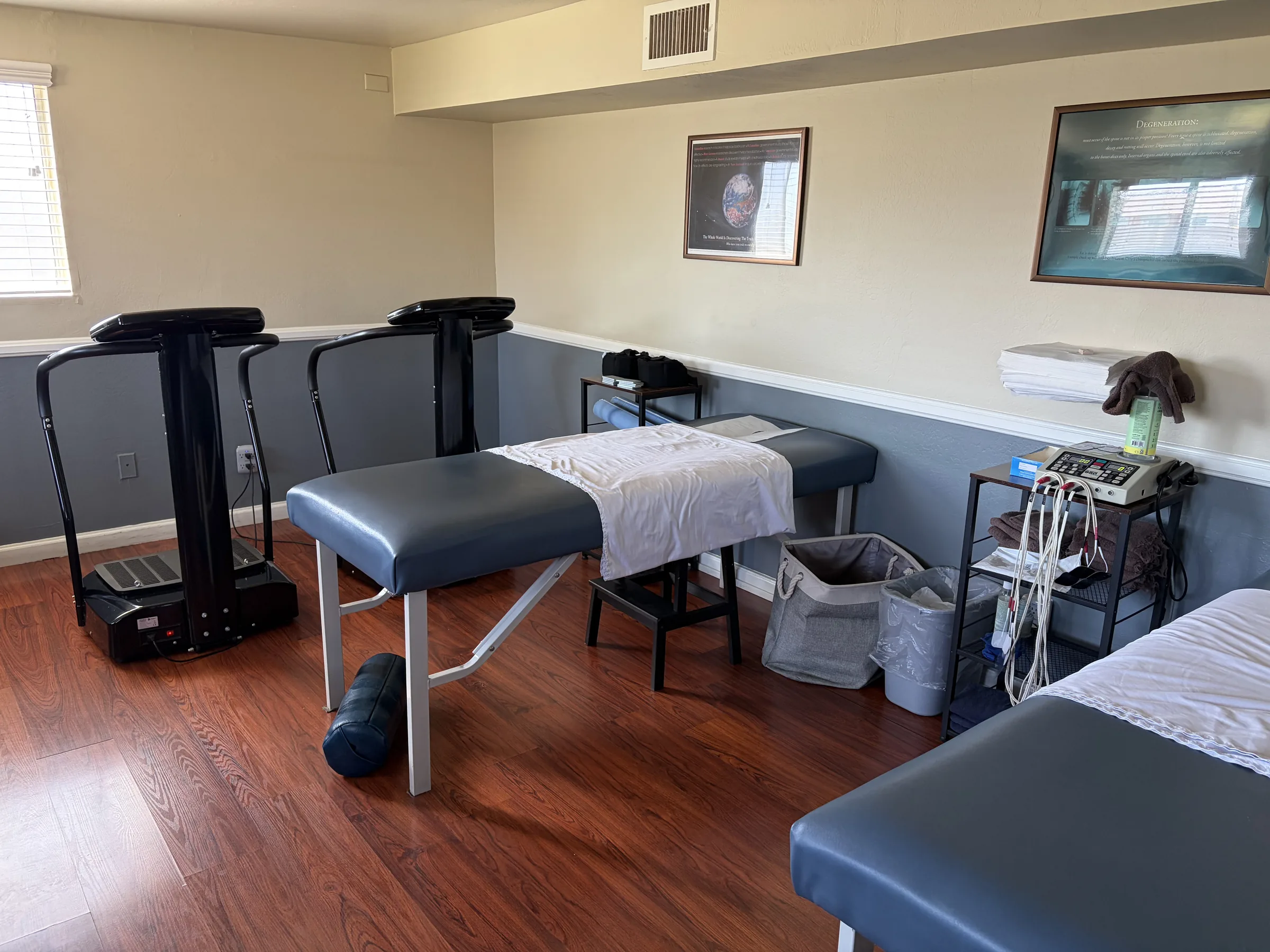 Chiropractic treatment room with massage tables, treadmills, and therapy equipment.