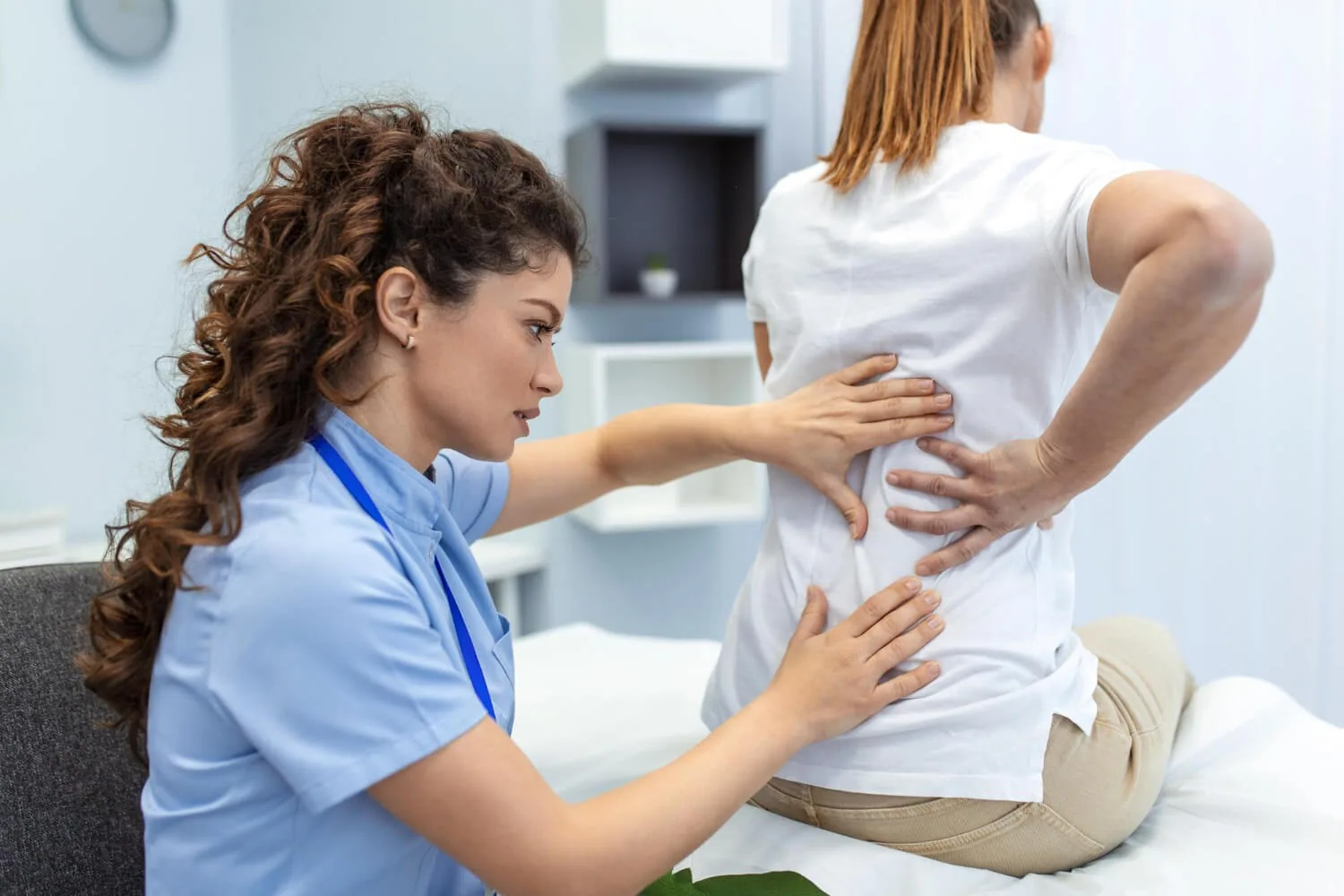 Chiropractor examining patient's back and spine in clinical setting.